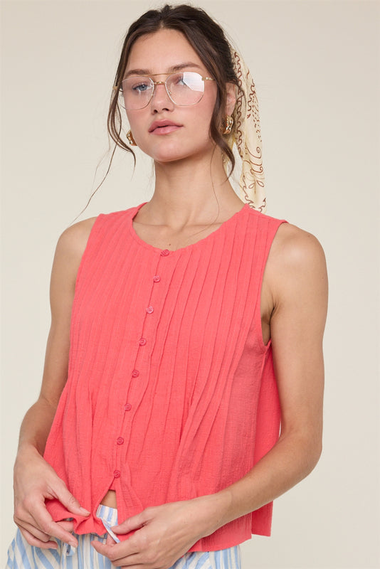 Woman wearing a coral sleeveless top with a neutral background