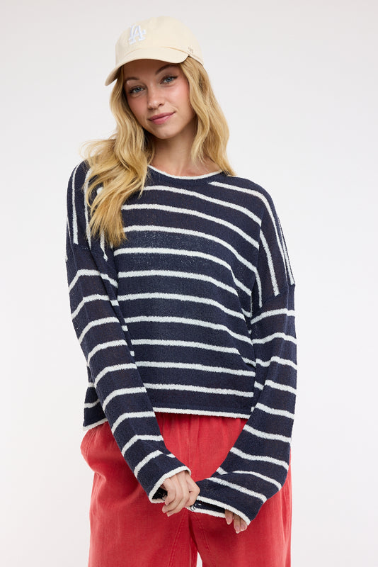 Woman wearing a striped sweater with a red bag and white shirt