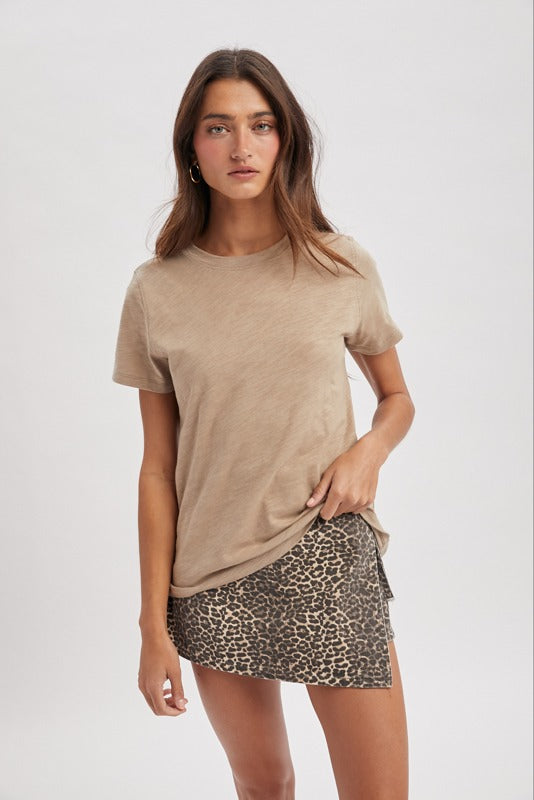 Woman wearing a beige t-shirt and leopard print skirt on a white background