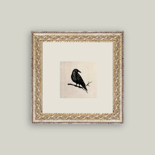 Framed artwork of a black bird on a branch against a light background