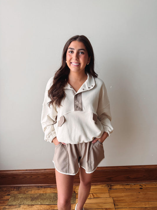 Woman wearing a beige outfit with a white wall background