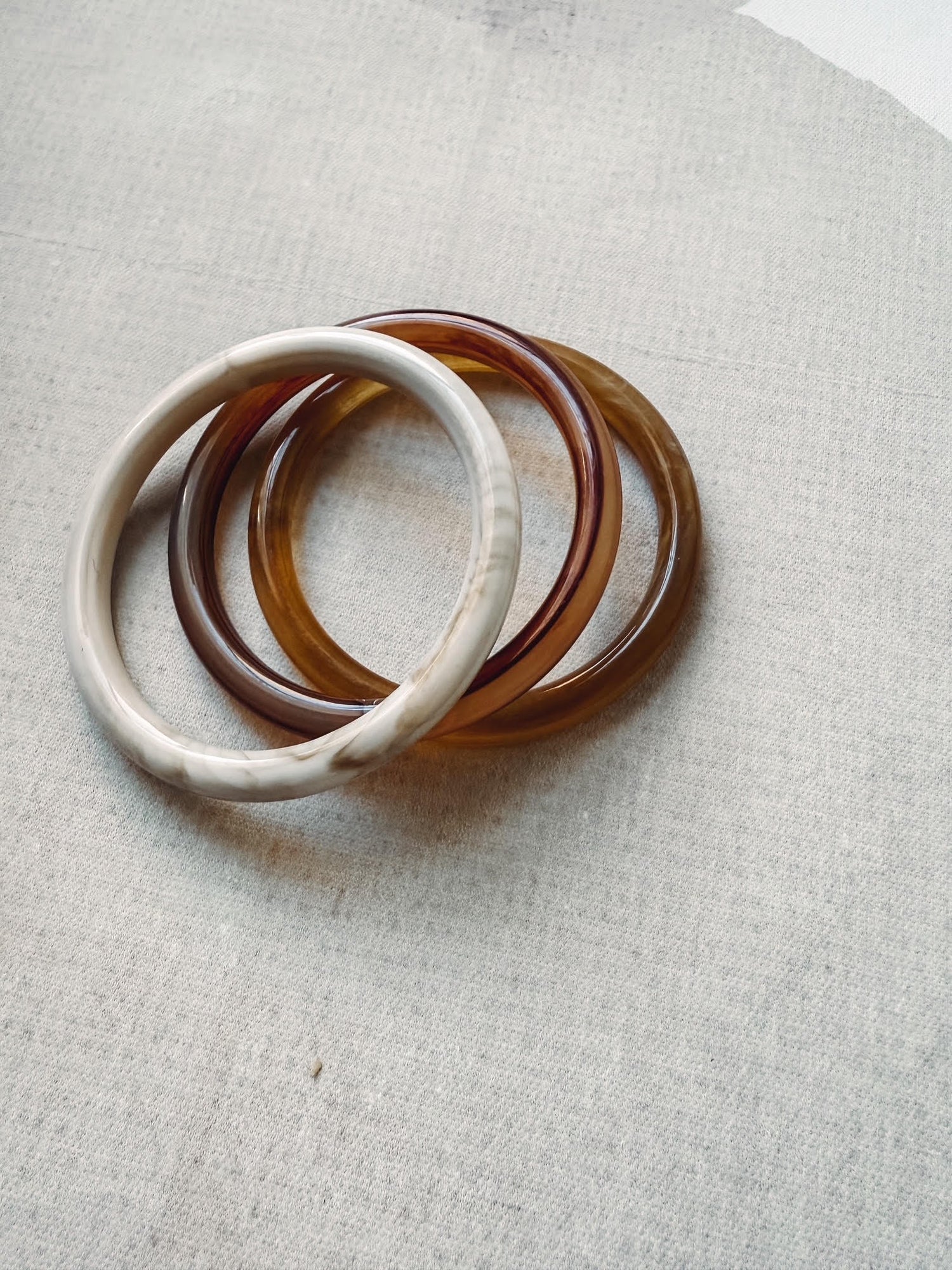 Set of three tortoiseshell bangles on a light gray fabric background