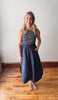Woman wearing a striped dress standing on a wooden floor with a white wall background