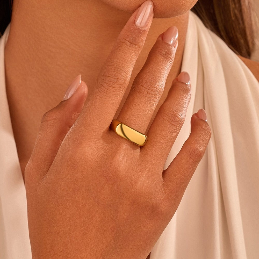 Close-up of a hand wearing a gold ring with a soft focus background