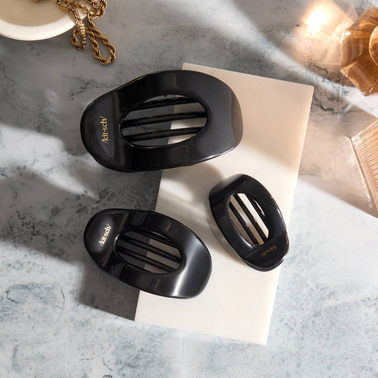 Black hair clips on a textured surface with a neutral background
