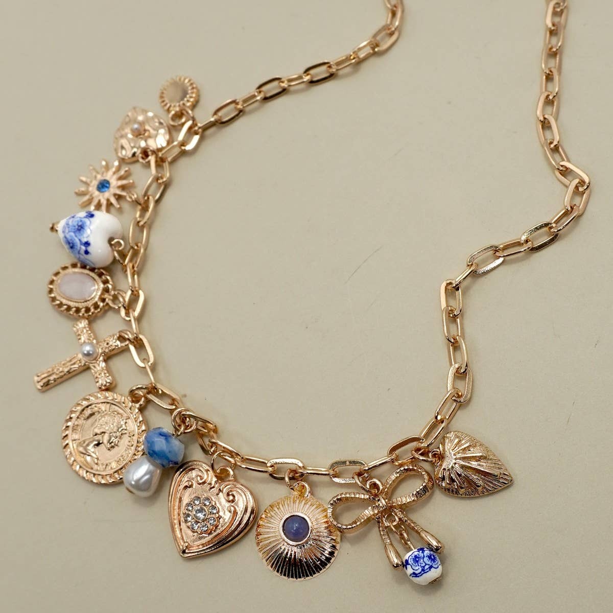 Gold necklace with various charms on a beige background