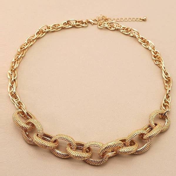 Gold chain necklace on a beige background