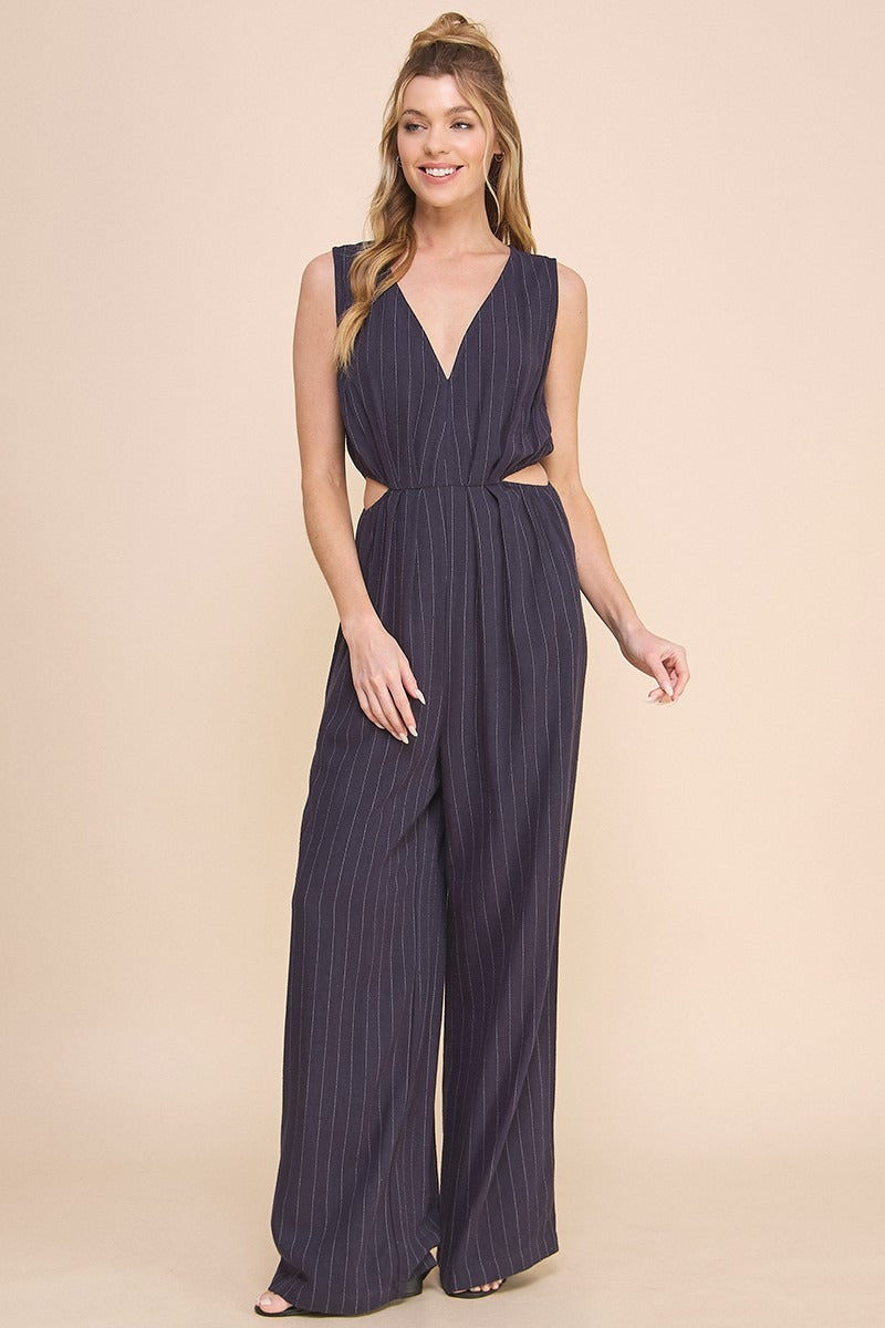 Woman wearing a navy pinstripe jumpsuit on a beige background