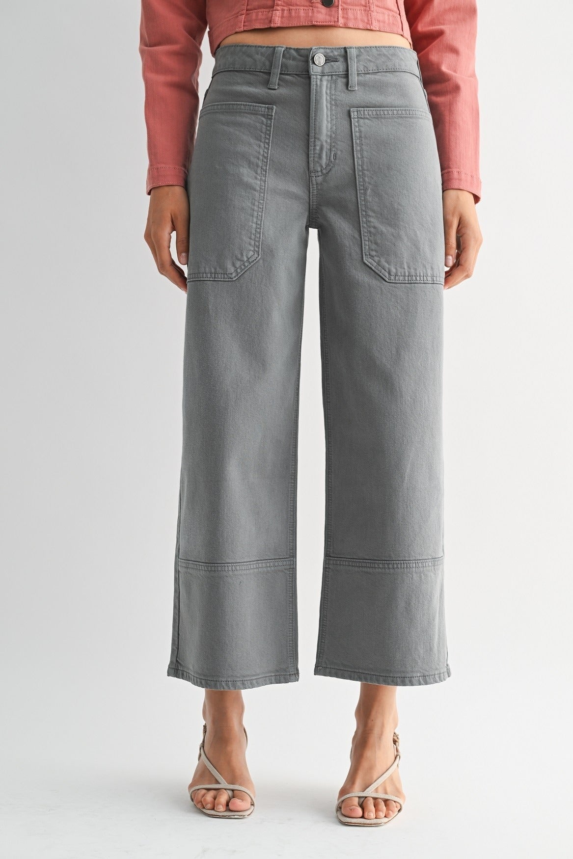 Person wearing gray wide-leg jeans and a pink top on a light gray background