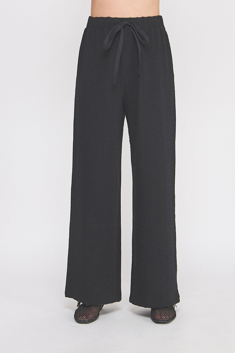 Black wide-leg pants with a tie waist on a white background