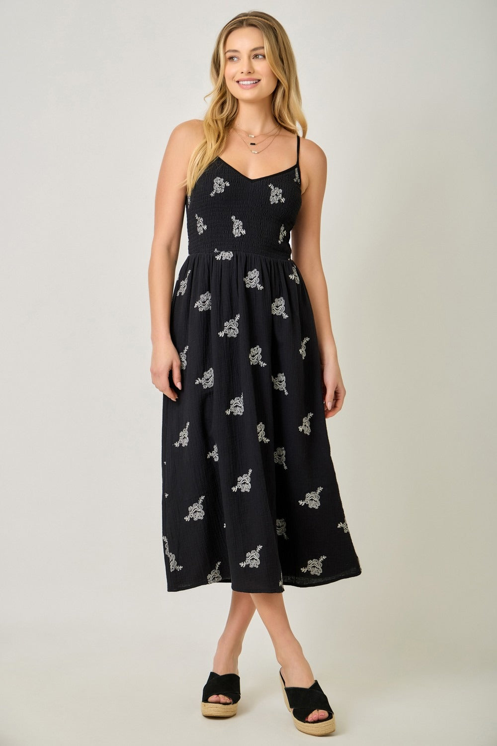 Woman wearing a black dress with white patterns on a plain background