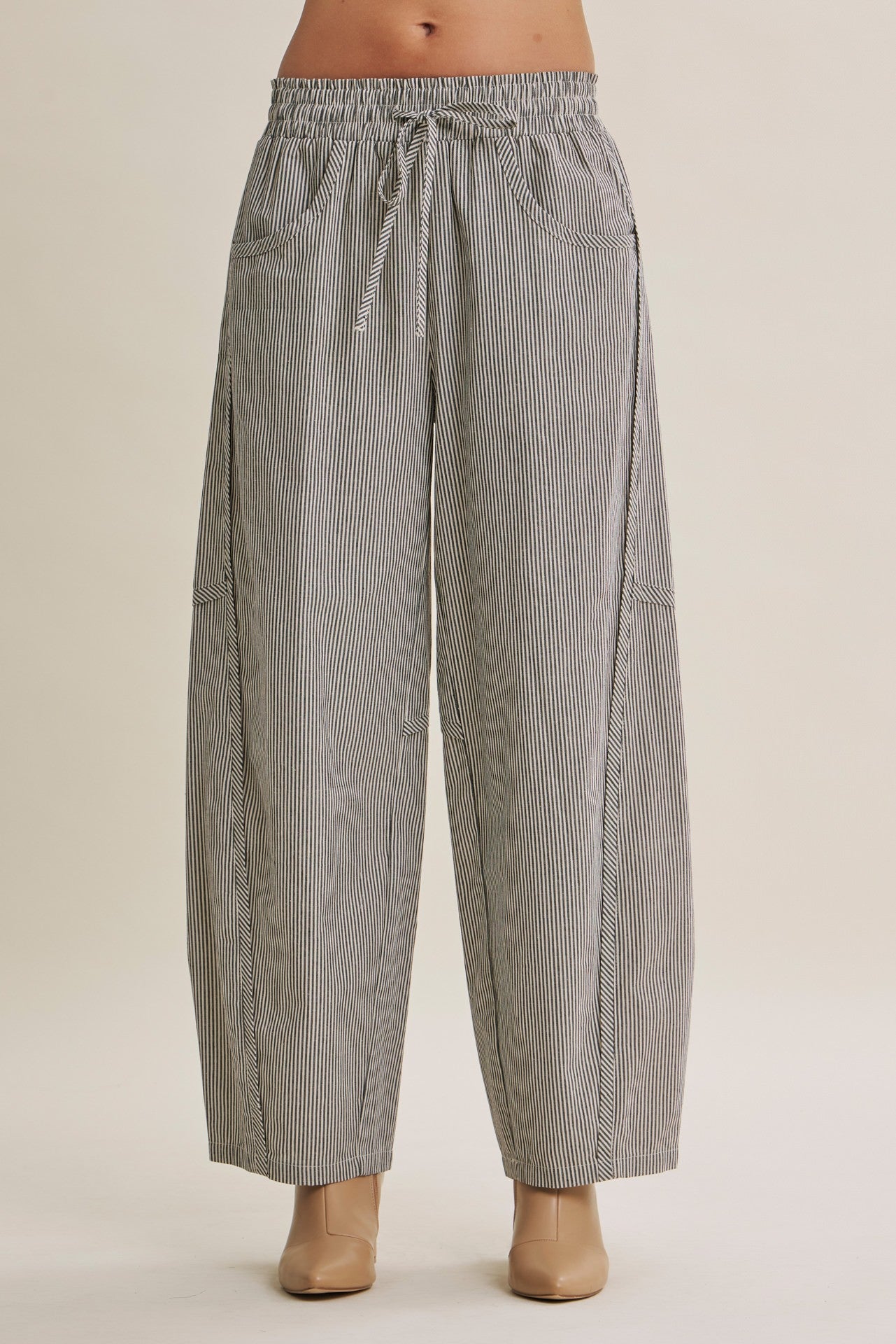 Gray vertically striped wide-leg pants with an elastic drawstring waist, modeled on a mannequin against a plain beige studio background.