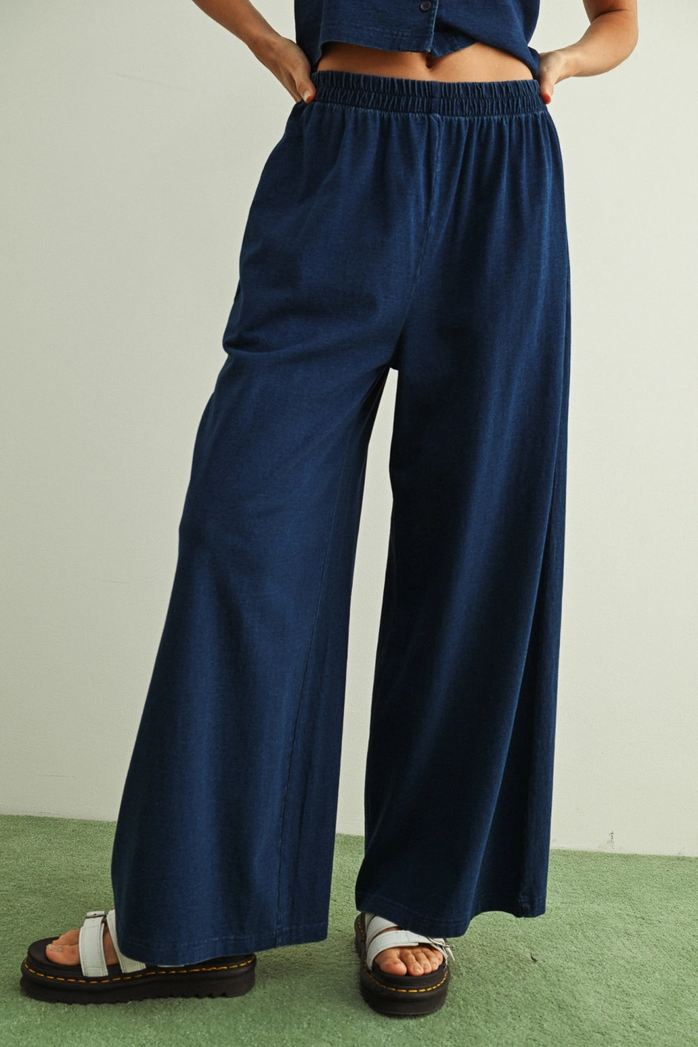 Person wearing navy wide-leg pants on a plain background