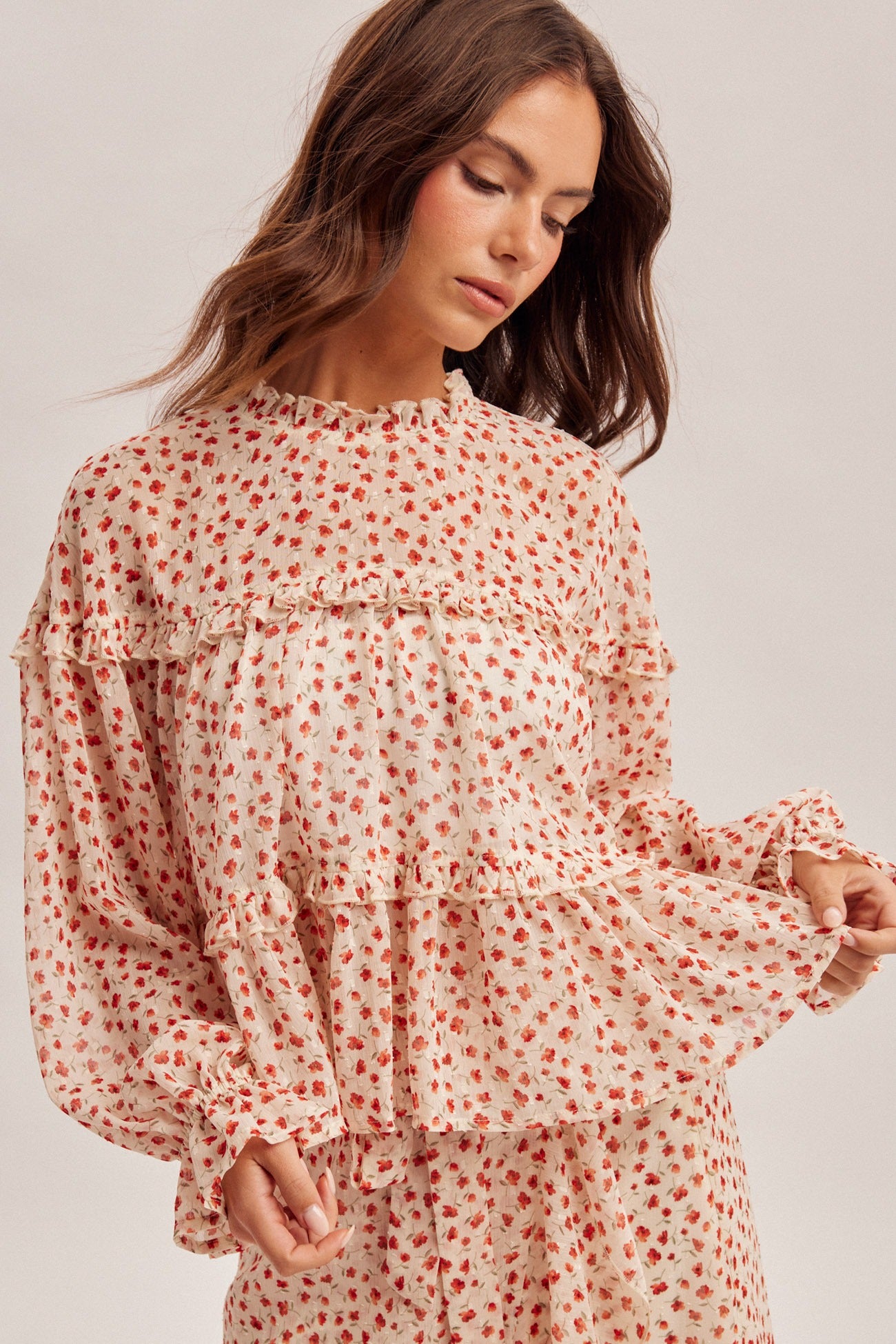 Woman wearing a floral blouse with long sleeves on a plain background