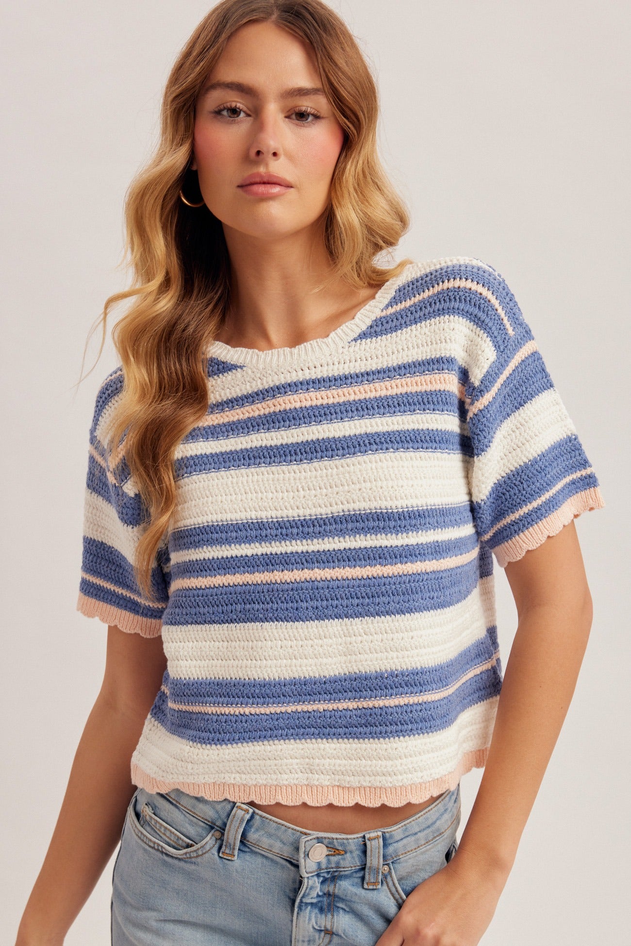 Woman wearing a striped short-sleeve sweater against a plain background