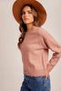 Woman wearing a pink sweater and brown hat against a beige background