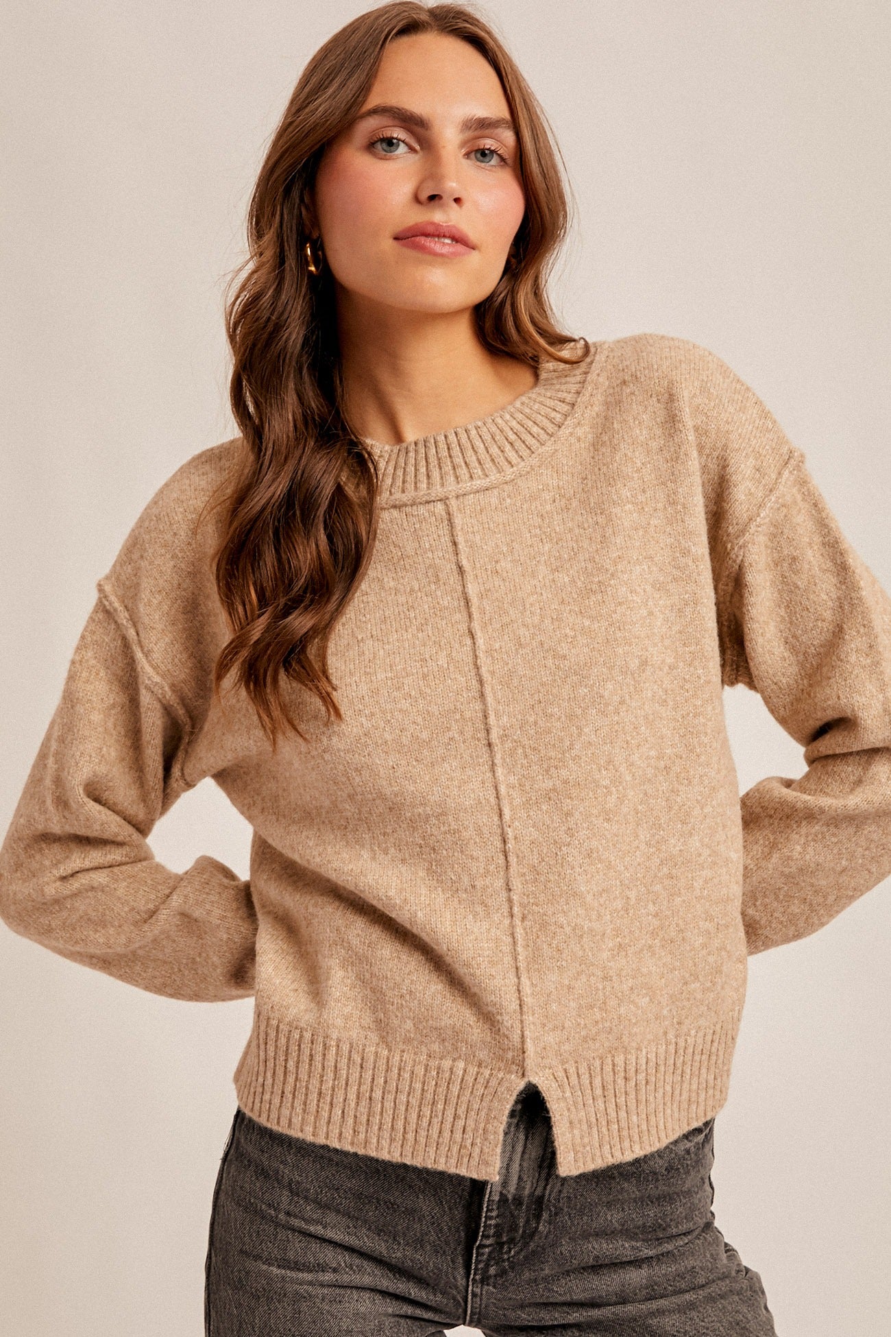 Woman wearing a beige sweater against a plain background