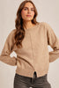 Woman wearing a beige sweater against a plain background