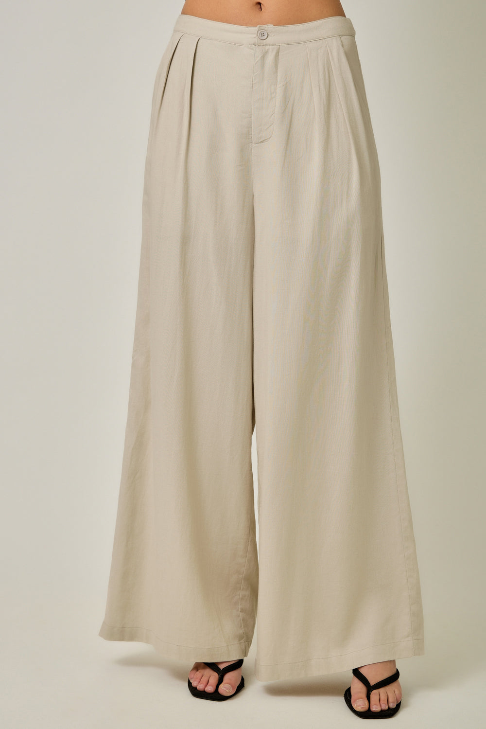 Beige wide-leg pants worn by a person on a white background