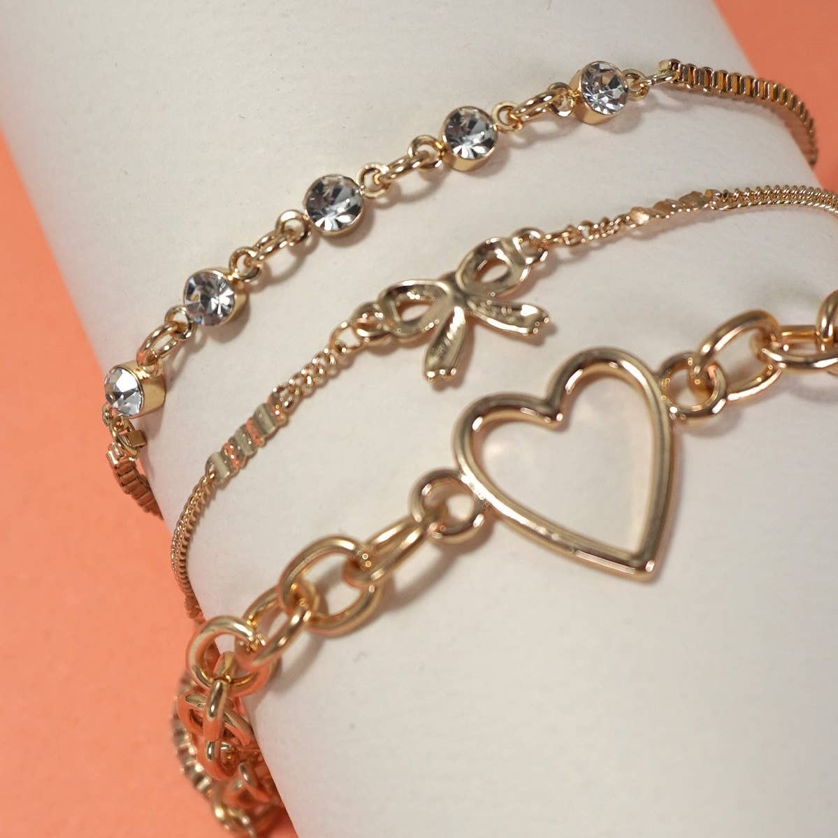 Gold bracelet with heart charm on a white surface