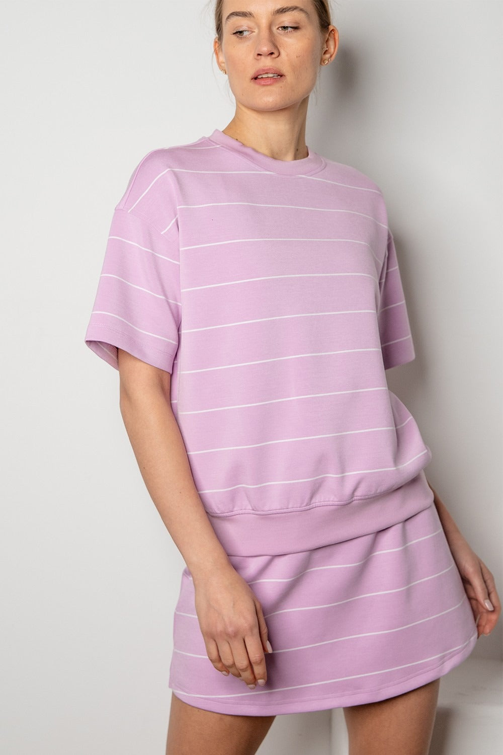 Woman wearing a matching lavender striped t-shirt and skirt set against a plain background