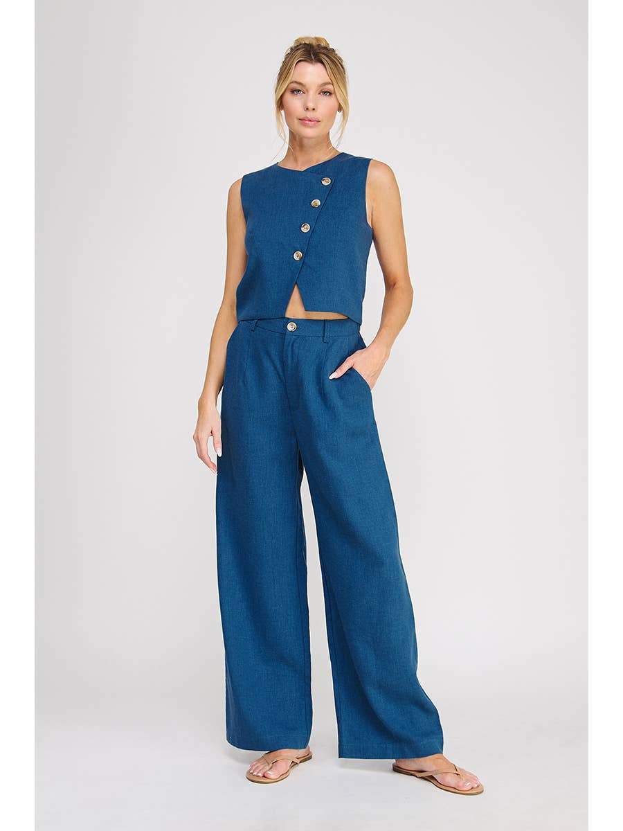 Woman wearing a blue sleeveless top and wide-leg pants on a white background