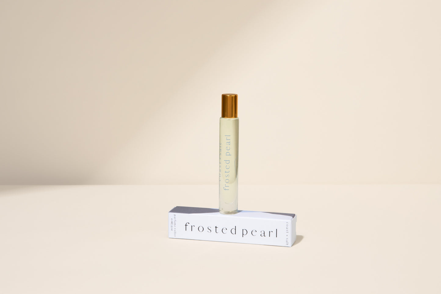 Roll-on bottle with 'Frosted Pearl' packaging on a beige background