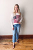 Woman wearing a sweater with a flag design standing against a plain background.