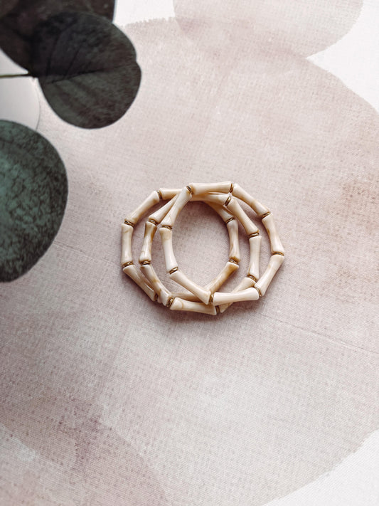 Decorative wreath made of bamboo on a textured surface with green leaves in the background