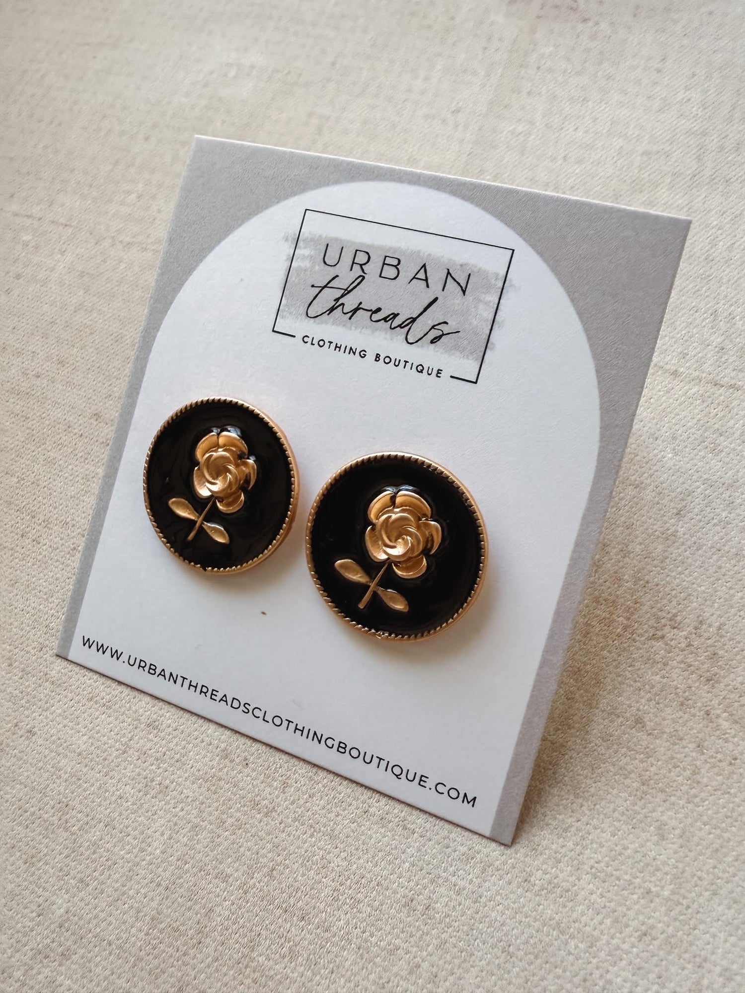 Black and gold rose earrings on a card from Urban Threads Clothing Boutique.
