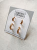 Gold hoop earrings on a 'Urban Threads' branded card against a light background