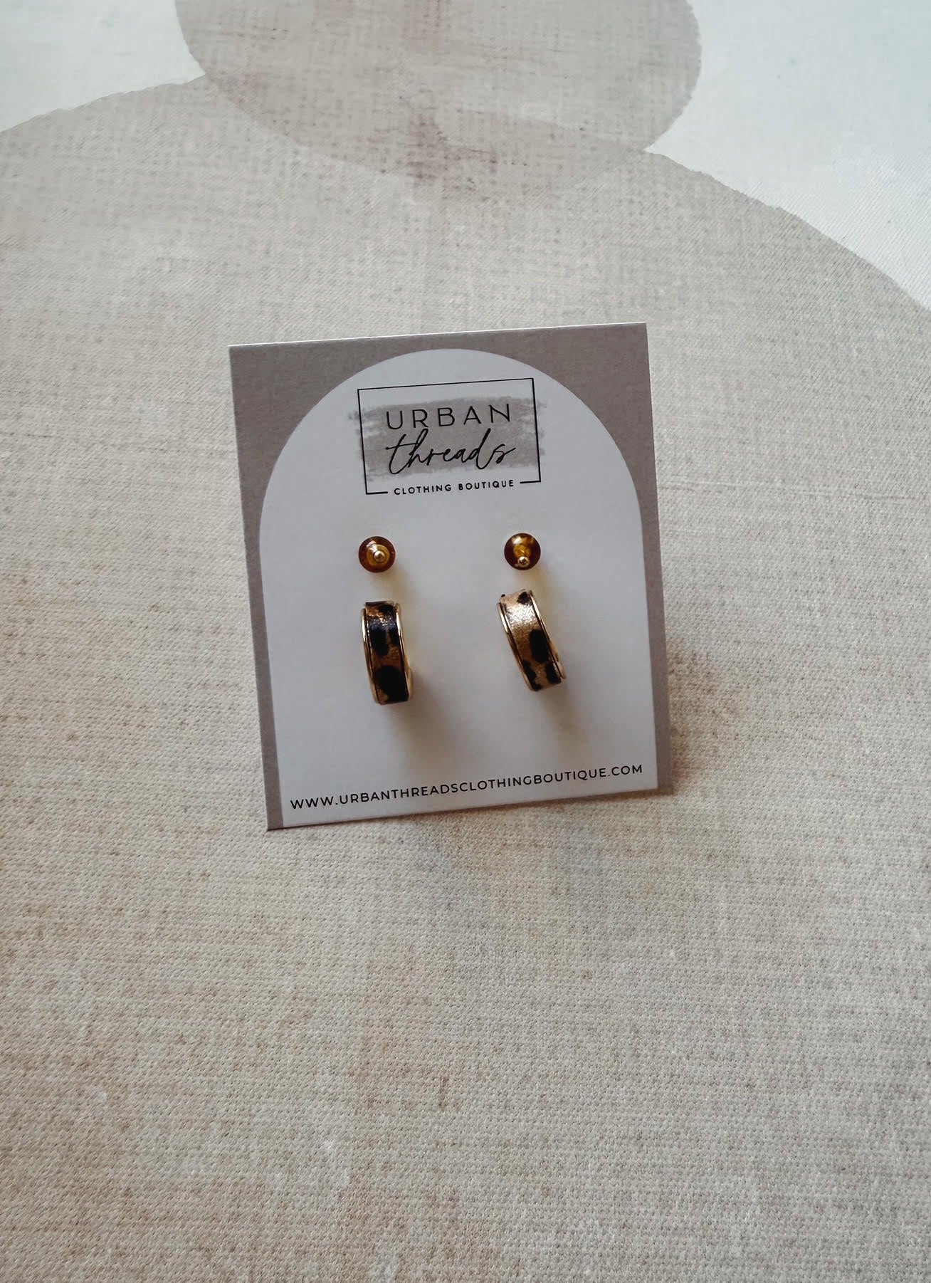 Set of earrings on a card with 'Urban Threads' branding on a textured beige background