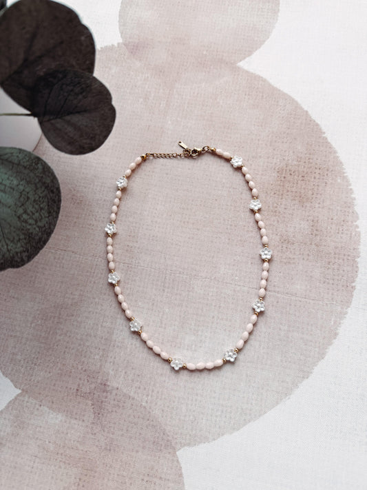 Necklace with pink beads and small flowers on a floral-patterned surface