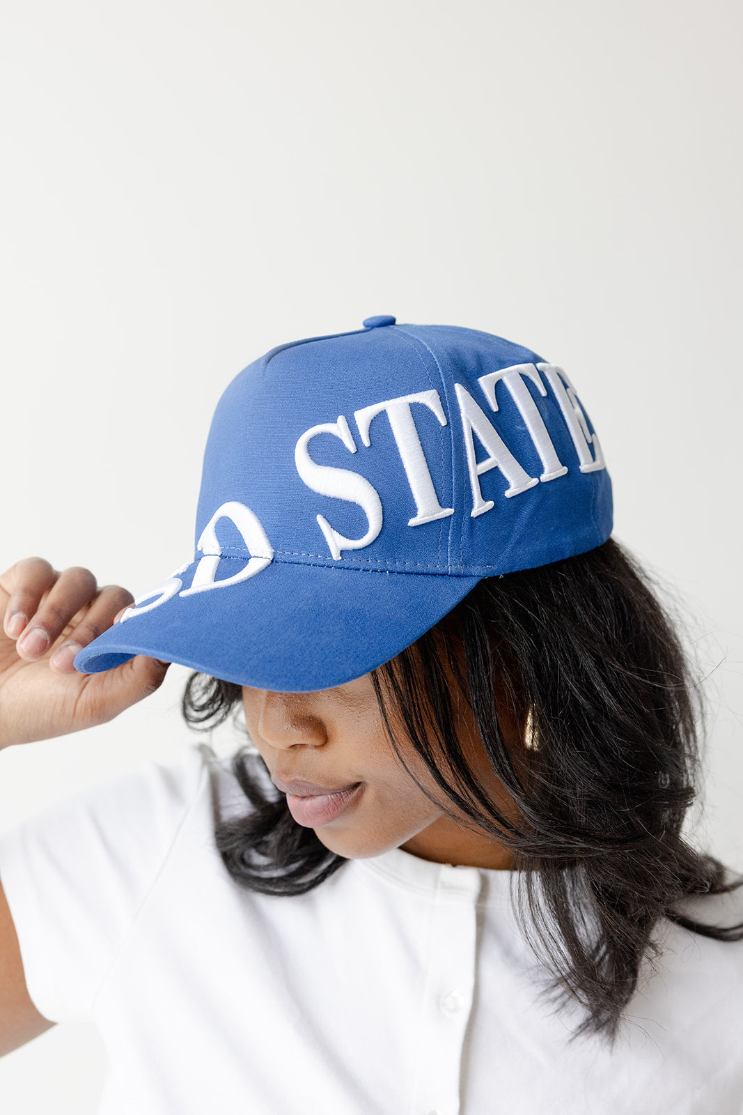 A person wearing a royal blue baseball cap with white 'UNITED STATES' text, photographed against a plain light background.