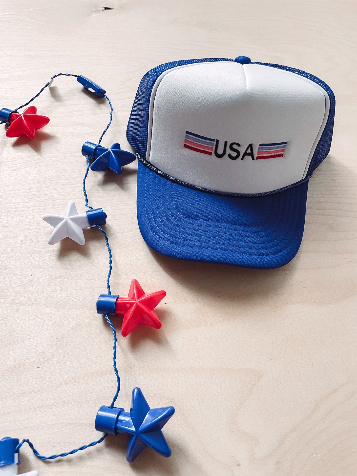 Blue and white cap with 'USA' logo next to star-shaped decorations on a light wooden surface