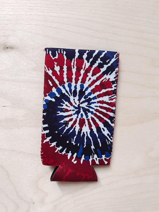 A red, white, and blue tie-dye koozie laid flat on a wooden surface.