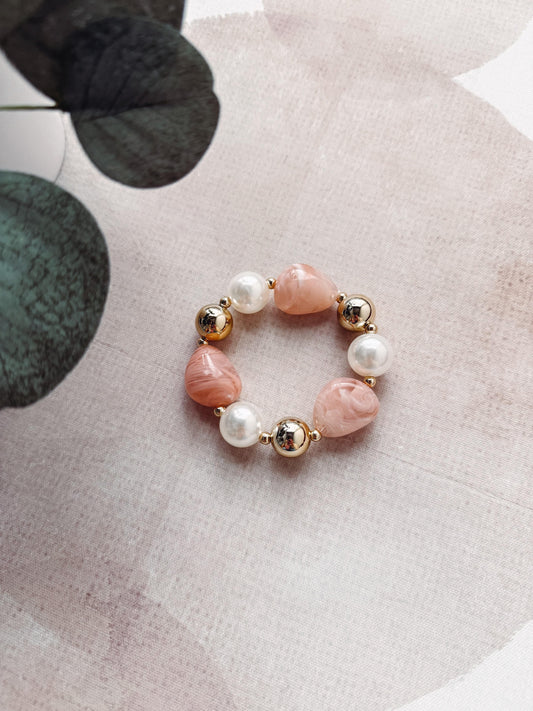 Beaded bracelet with pink and gold beads on a floral background