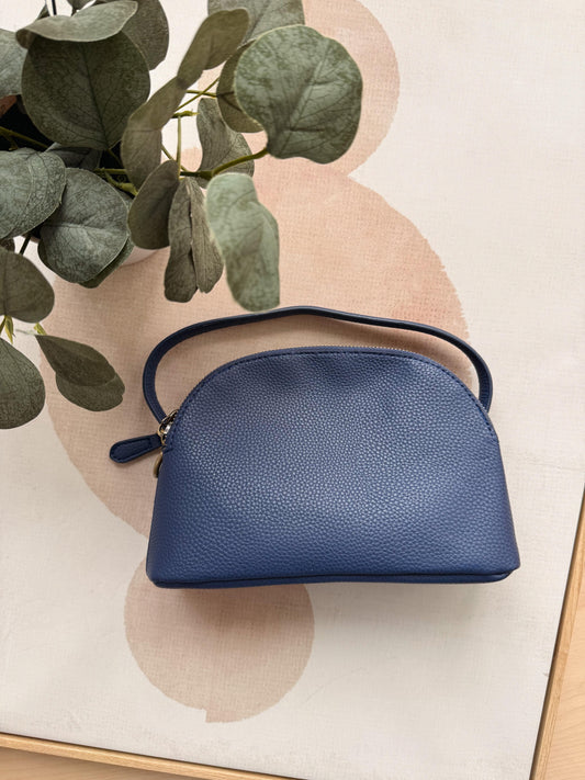 Blue handbag on a decorative surface with green leaves