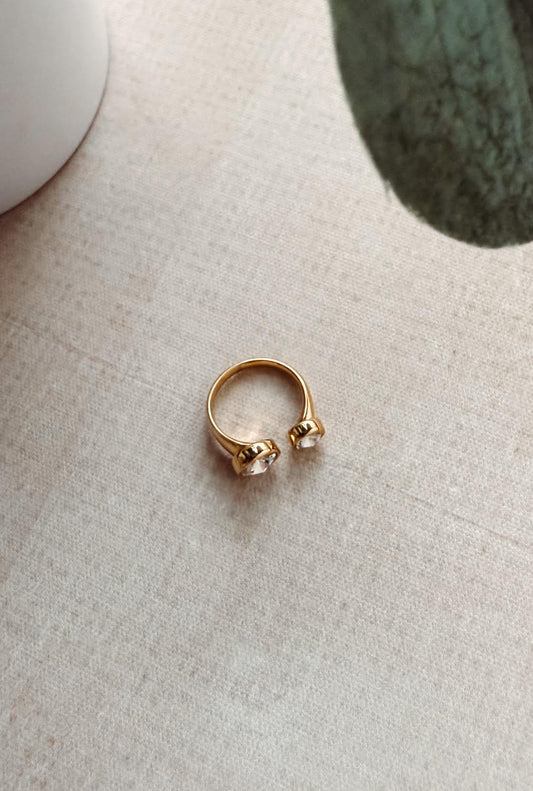 Gold ring with two small stones on a textured surface
