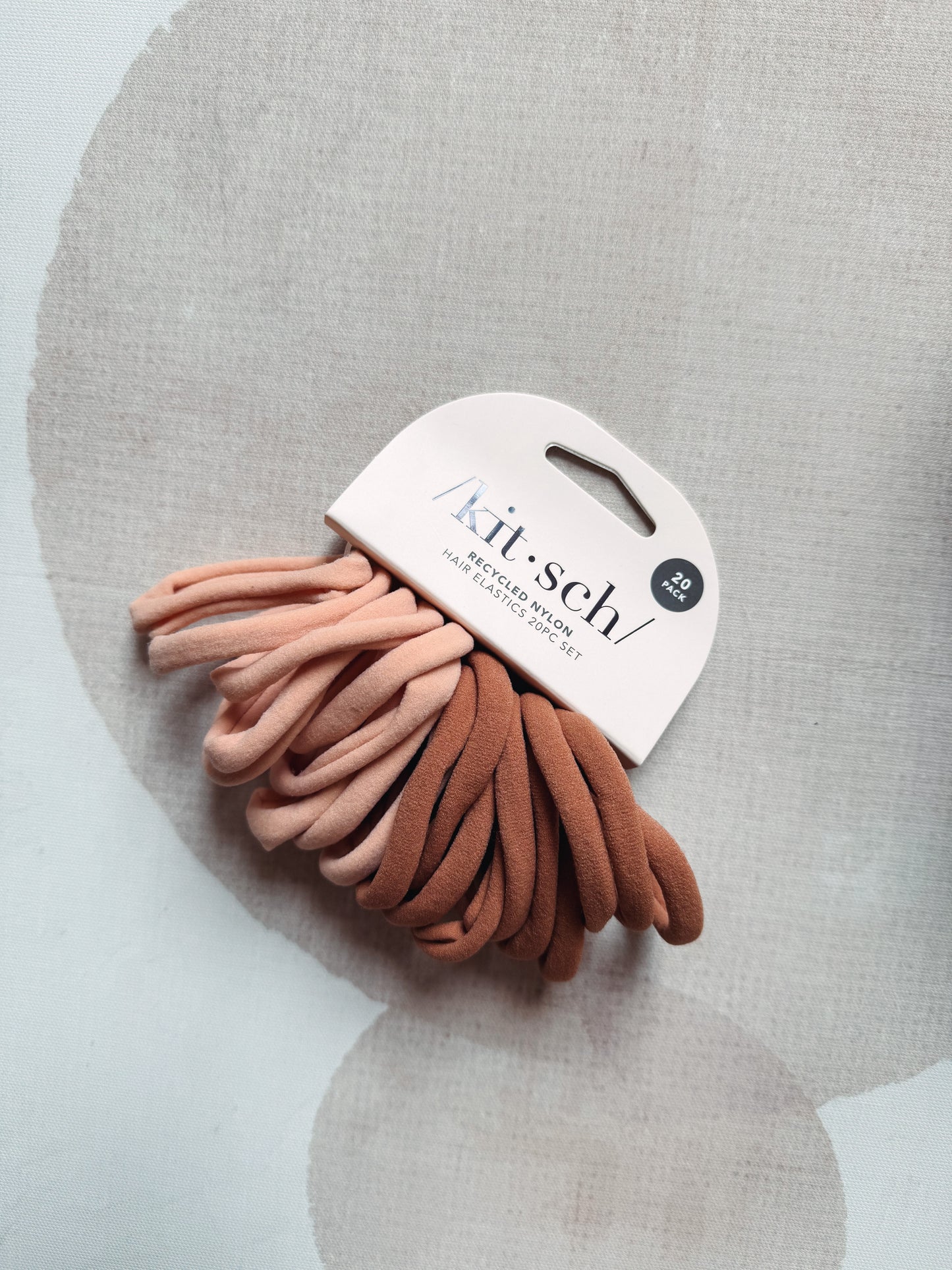 Set of hair ties in pink and brown on a 'kit-seh!' branded card against a gray background