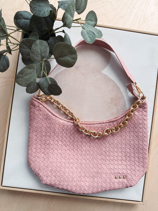 Pink handbag with gold chain strap on a light background