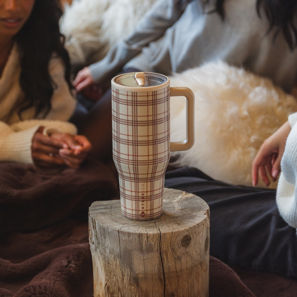 Plaid-patterned tumbler on a wooden block with people sitting around
