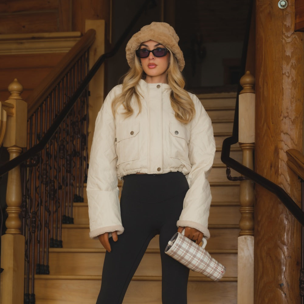 Woman in a white jacket and black pants standing on a staircase