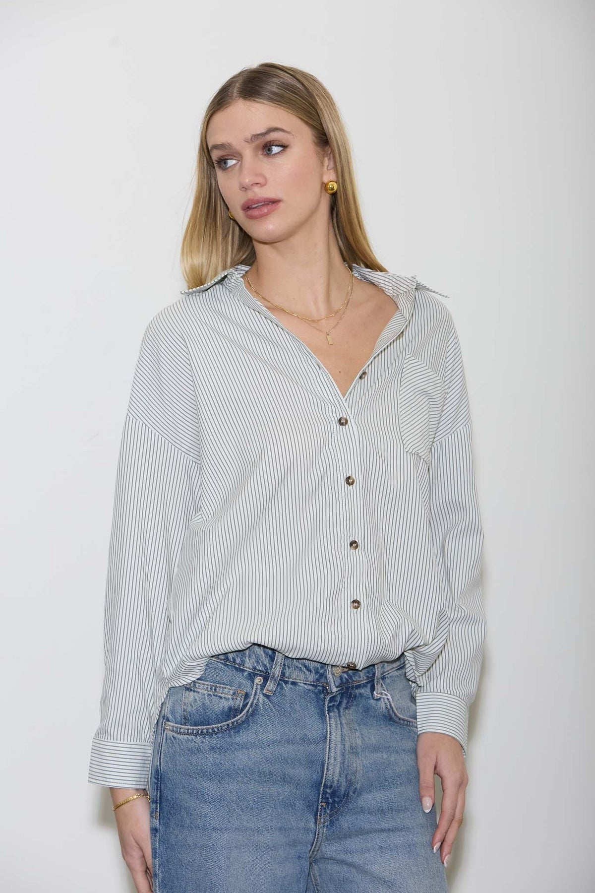 Woman wearing a striped shirt and jeans against a white background