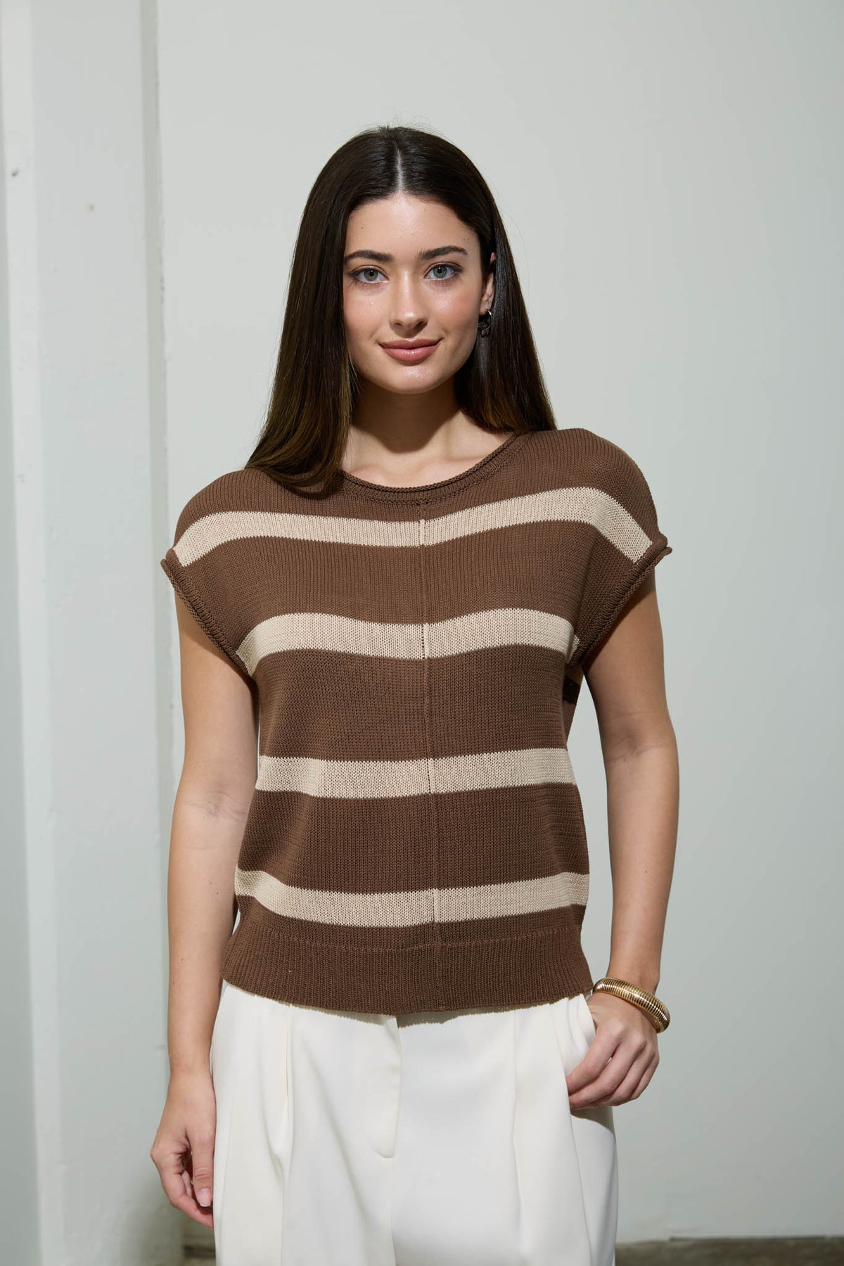 Woman wearing a brown and beige striped sweater against a plain background
