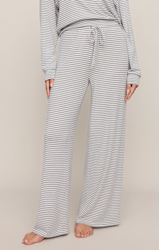 Person wearing a striped long-sleeve top and wide-leg pants on a neutral background