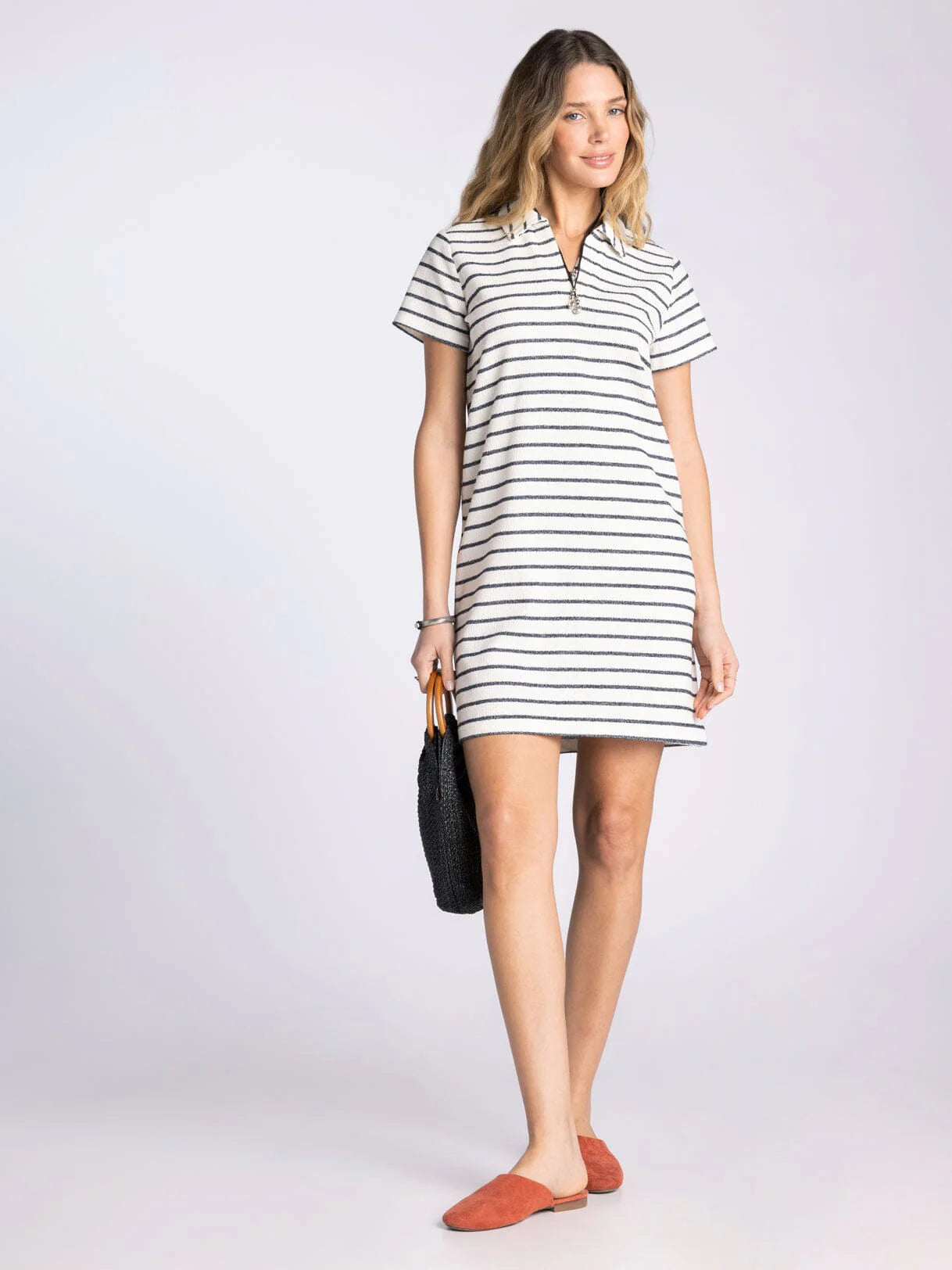 Woman wearing a black and white striped dress on a plain background