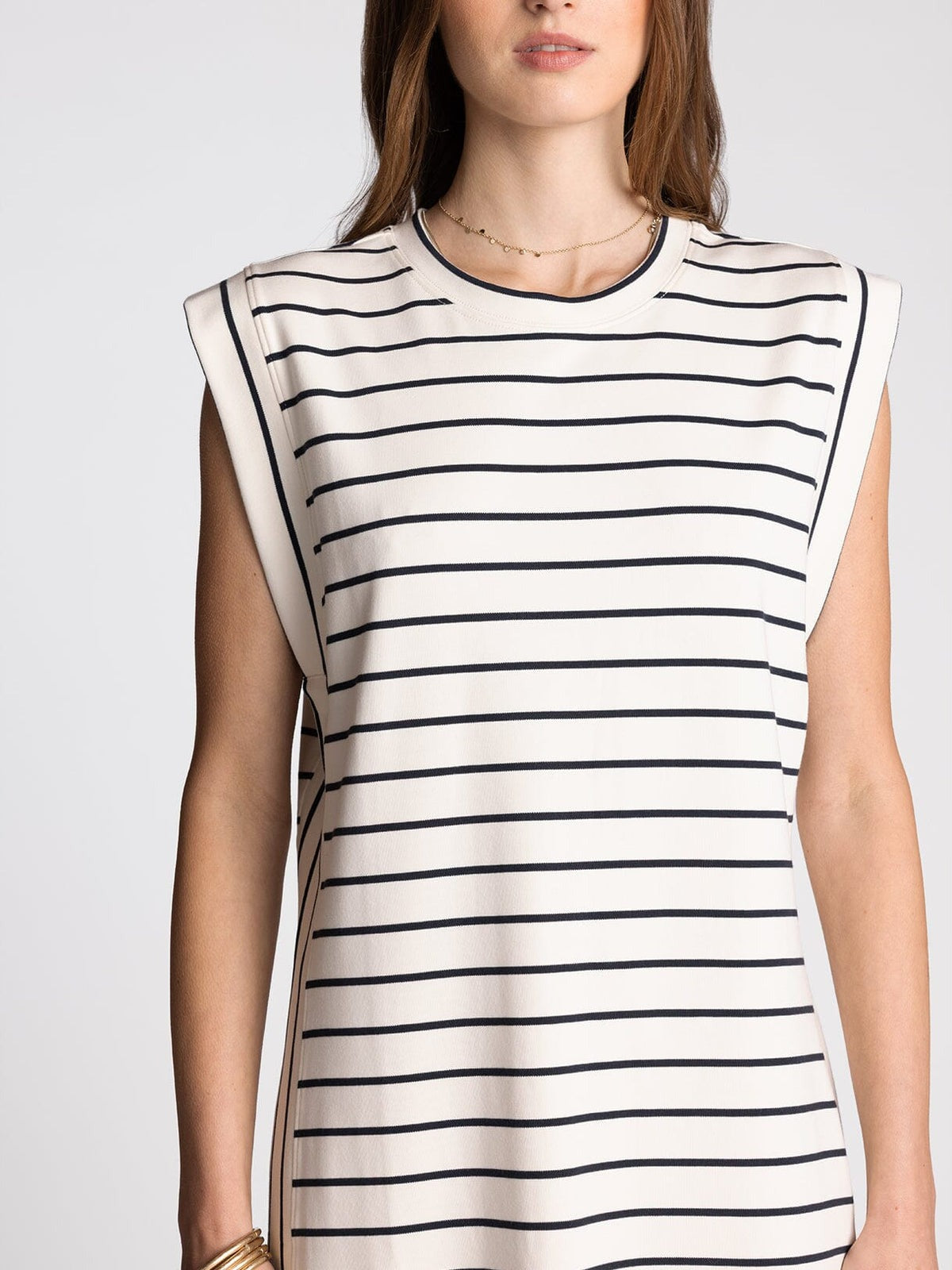 Woman wearing a sleeveless dress with black horizontal stripes on a plain background