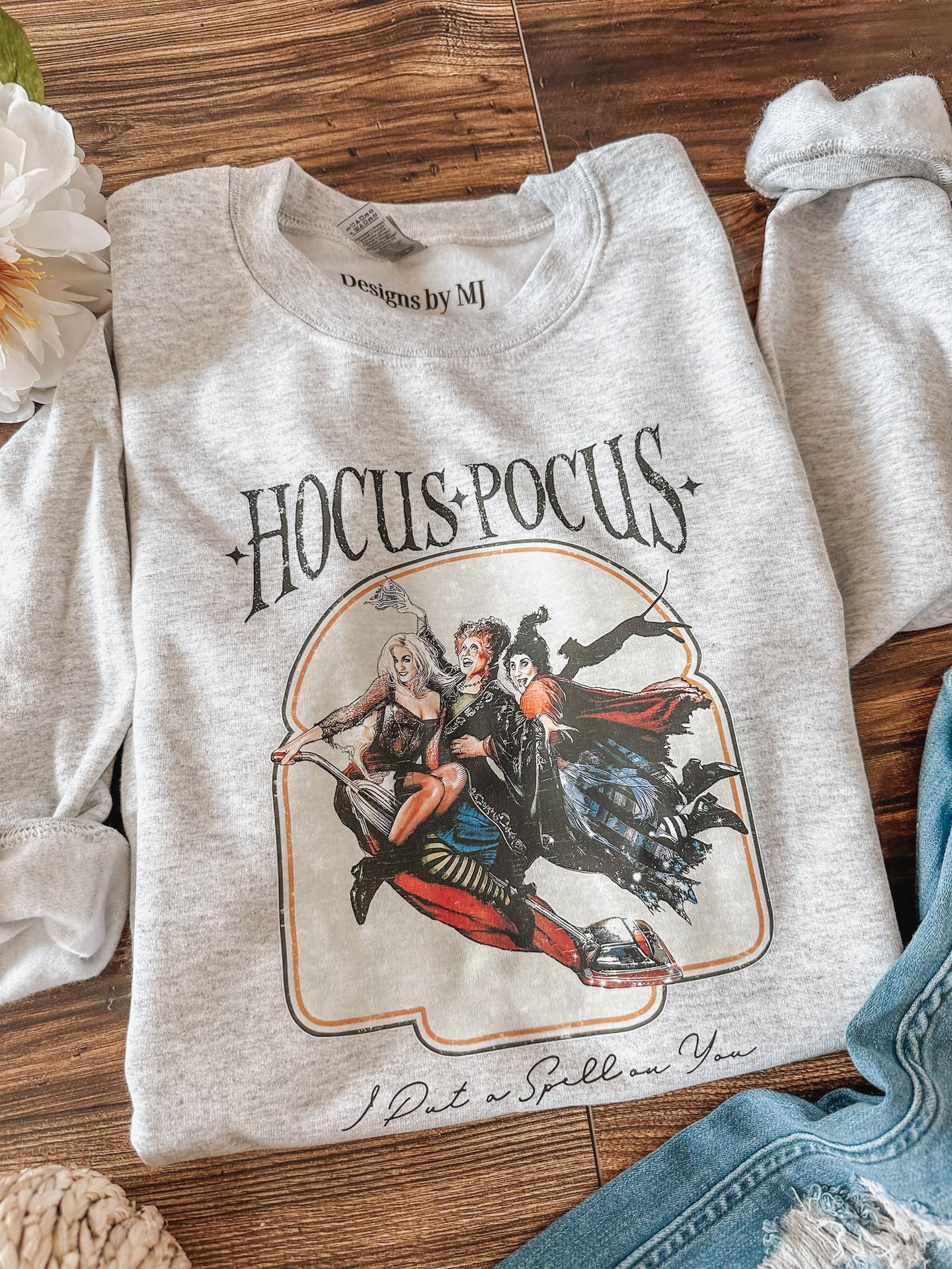 Gray sweatshirt with 'Hocus Pocus' design on a wooden surface