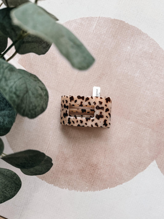 Leopard print product on a textured surface with green leaves